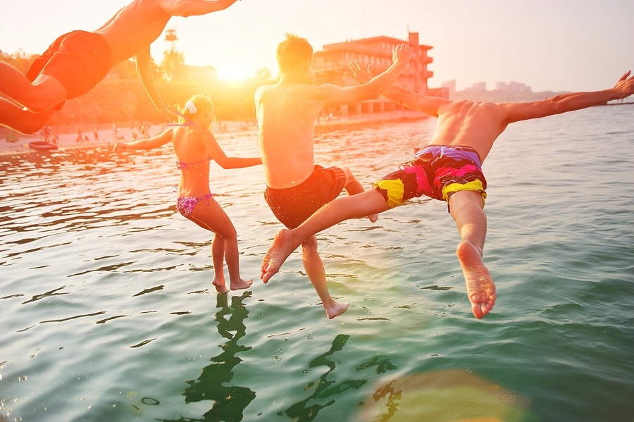 A group of friends jump into the water at the beach.